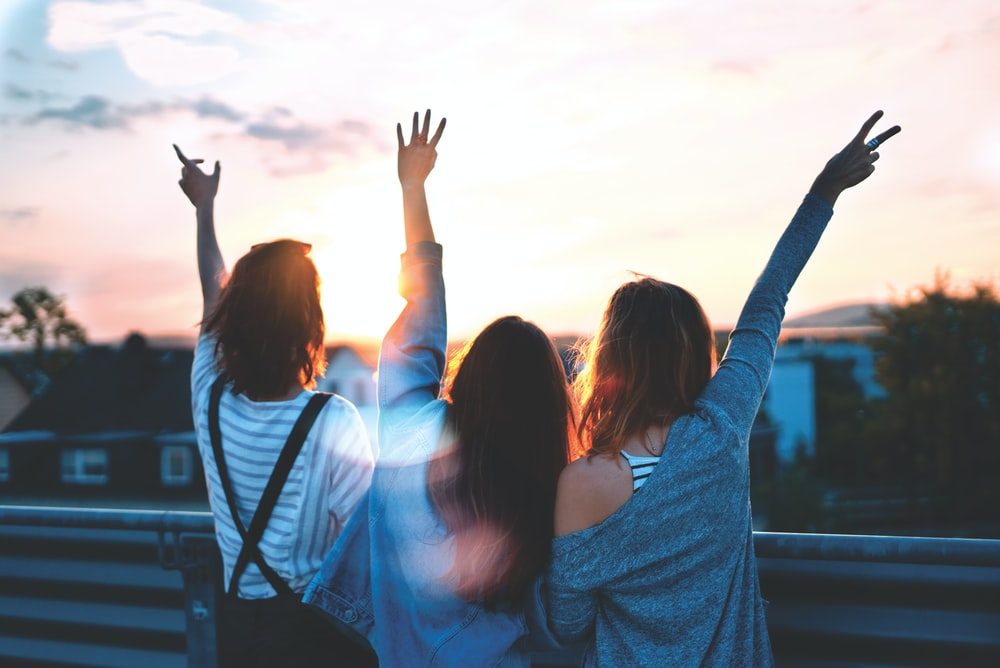 photo of three women lifting there hands 