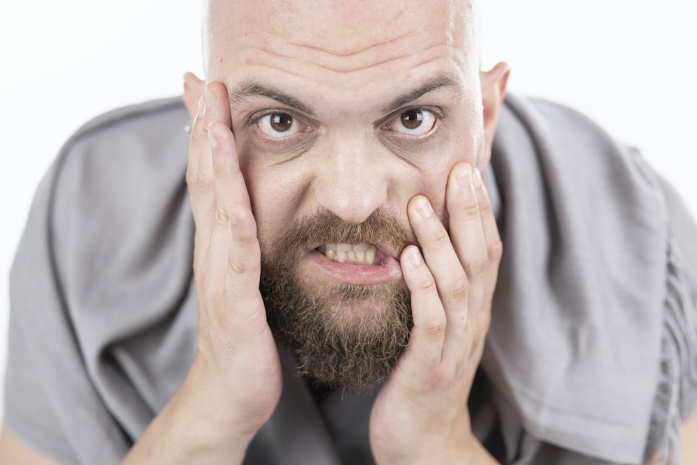 man in gray dress shirt covering his face